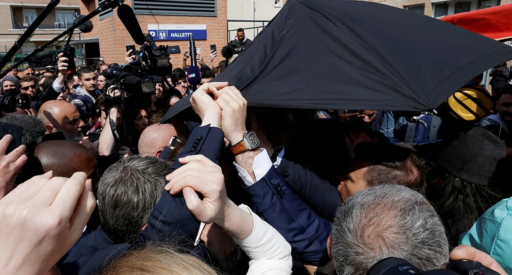 Security services cover Emmanuel Macron after a projectile is launched
